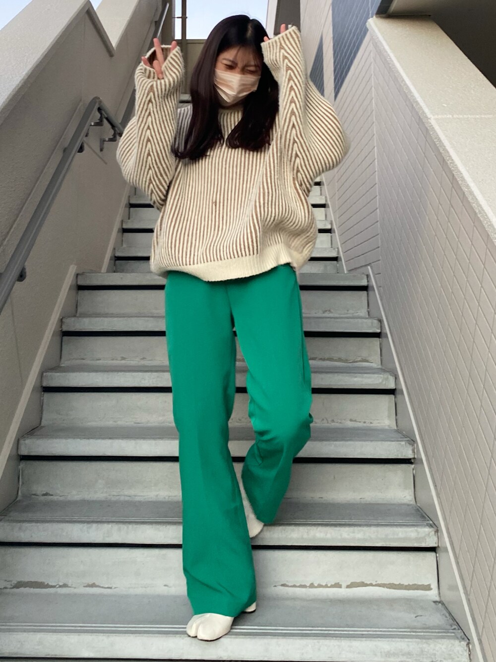 グリーン系のスラックス、ホワイト系のブーツ、ベージュ系のニット/セーターを着用したレディースの冬コーディネートの3枚目の写真