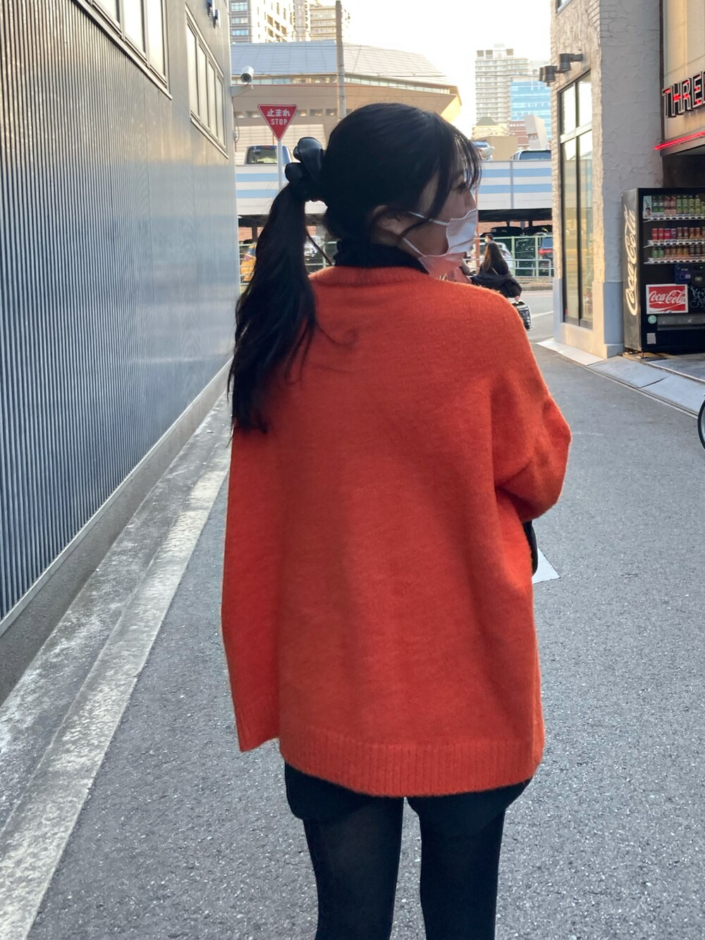 ブラック系のパンツ、オレンジ系のニット/セーター、ブラック系のブーツを着用したレディースの冬コーディネートの2枚目の写真