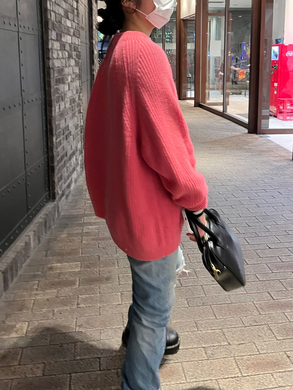 ブラック系のショルダーバッグ、ブルー系のデニムパンツ、ブラック系のブーツを着用したレディースの春コーディネートの2枚目の写真