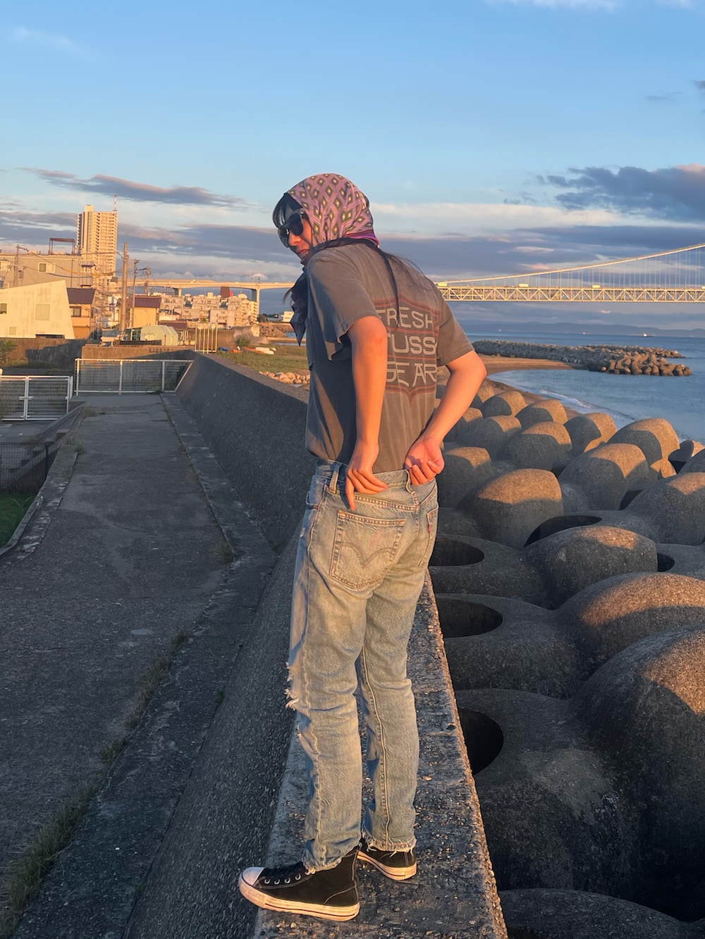 グレー系のTシャツ/カットソー、ブルー系のデニムパンツ、ブラック系のスニーカーを着用したレディースの夏コーディネートの2枚目の写真