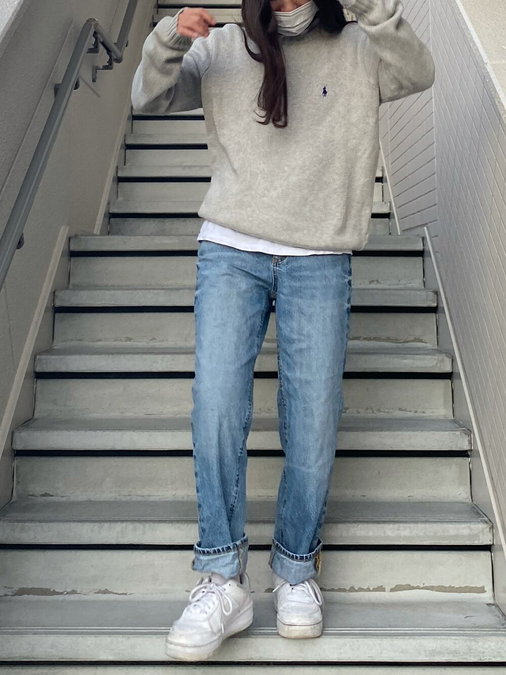 ブルー系のデニムパンツ、ホワイト系のスニーカー、グレー系のニット/セーターを着用したレディースの冬コーディネートの2枚目の写真