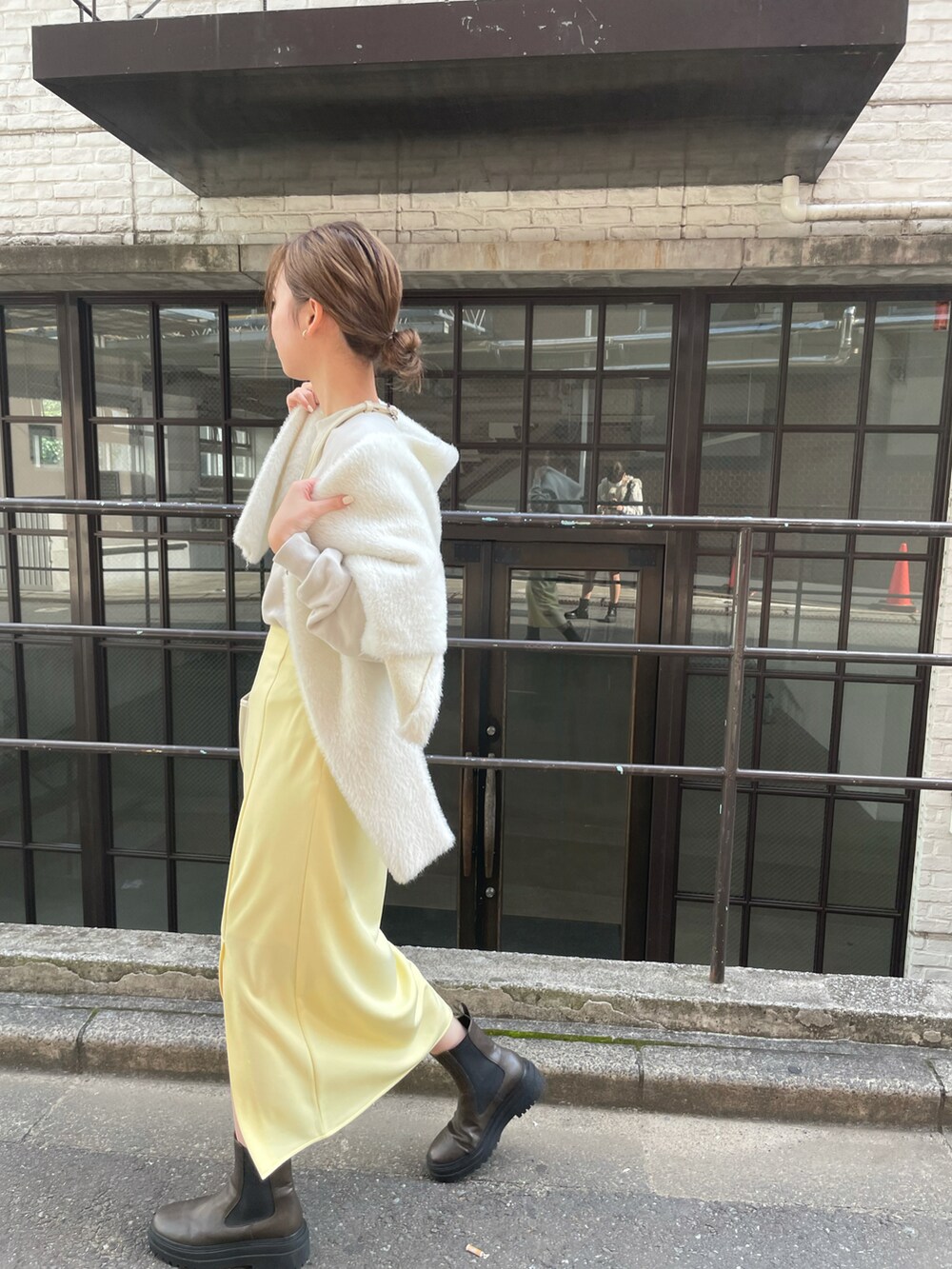 ホワイト系のカーディガン/ボレロ、イエロー系のスカート、グリーン系のブーツを着用したレディースの秋コーディネートの3枚目の写真