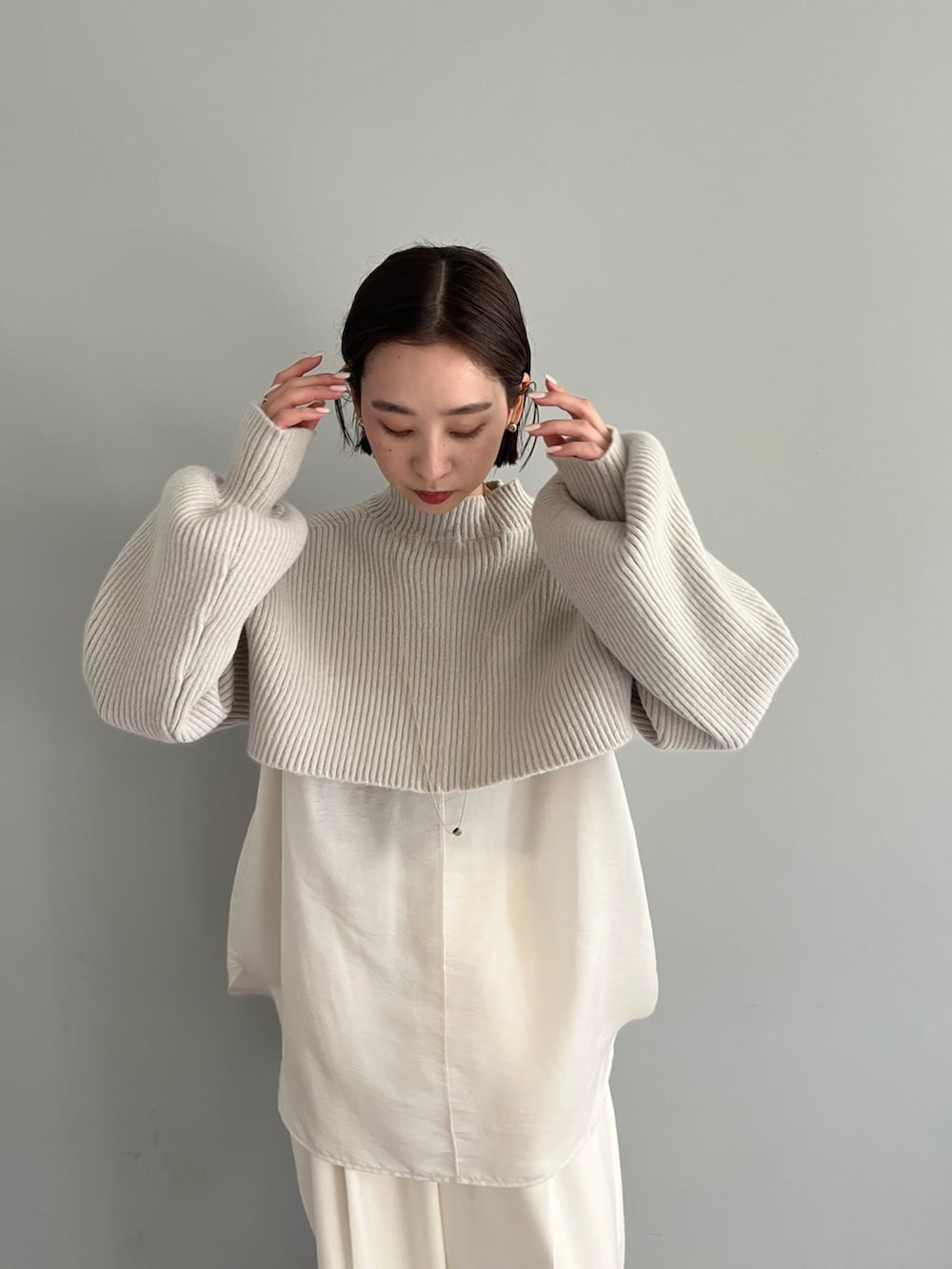 ベージュ系のニット/セーター、ホワイト系のスラックス、ブラック系のブーツを着用したレディースの秋コーディネートの2枚目の写真