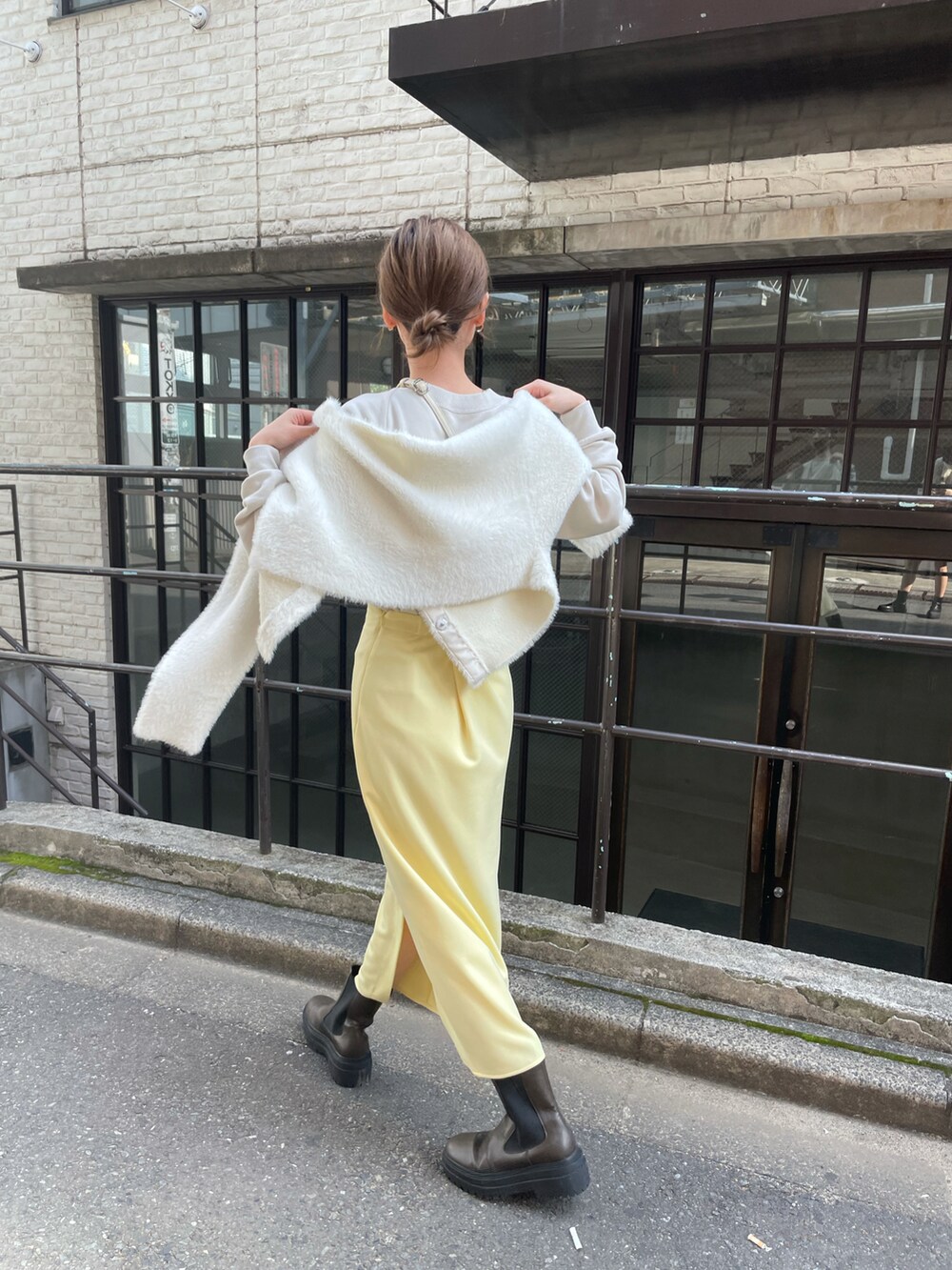 ホワイト系のカーディガン/ボレロ、イエロー系のスカート、グリーン系のブーツを着用したレディースの秋コーディネートの4枚目の写真