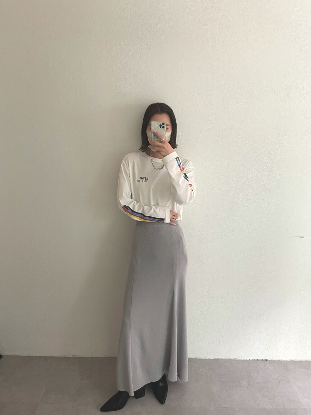 ホワイト系のTシャツ/カットソー、グレー系のスカート、ブラック系のブーツを着用したレディースの秋コーディネートの2枚目の写真