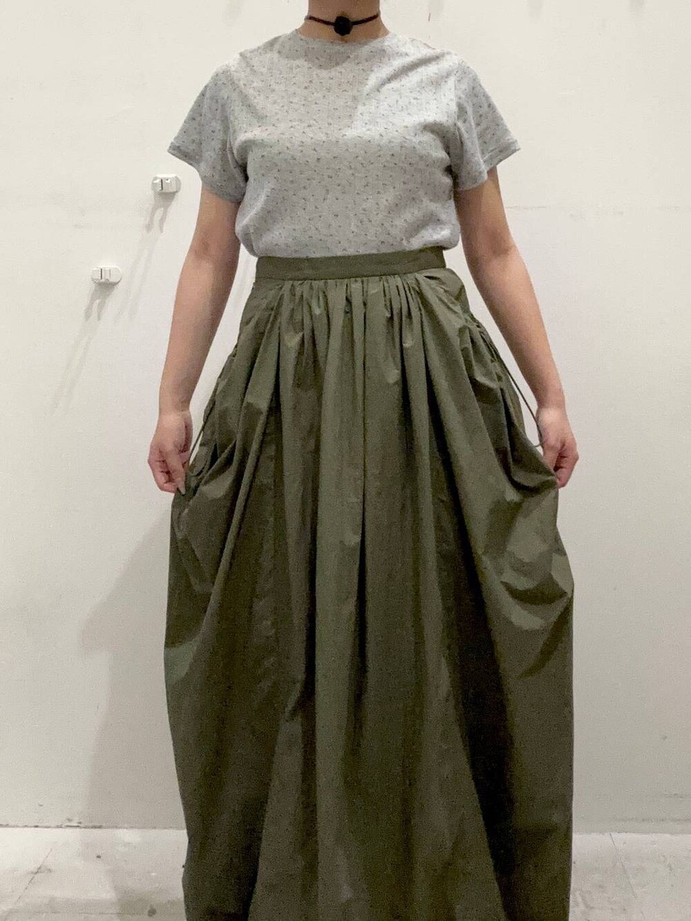 グリーン系のスカート、グレー系のTシャツ/カットソー、ブラック系のチョーカーを着用したレディースの夏コーディネートの2枚目の写真