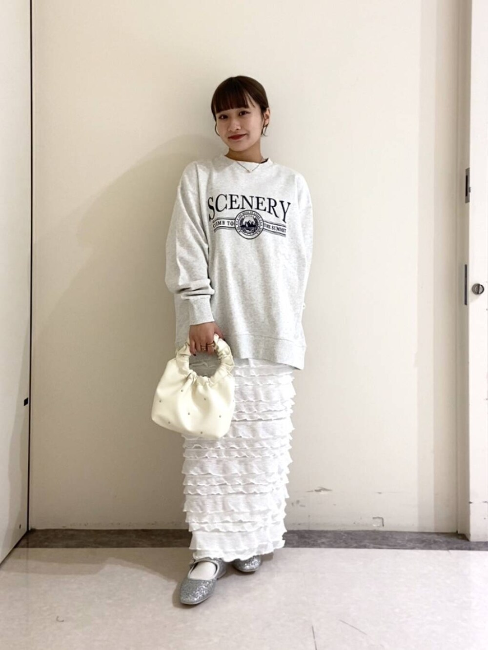 シルバー系のパンプス、グレー系のスウェット、ホワイト系のスカートを着用したレディースの春コーディネートの2枚目の写真