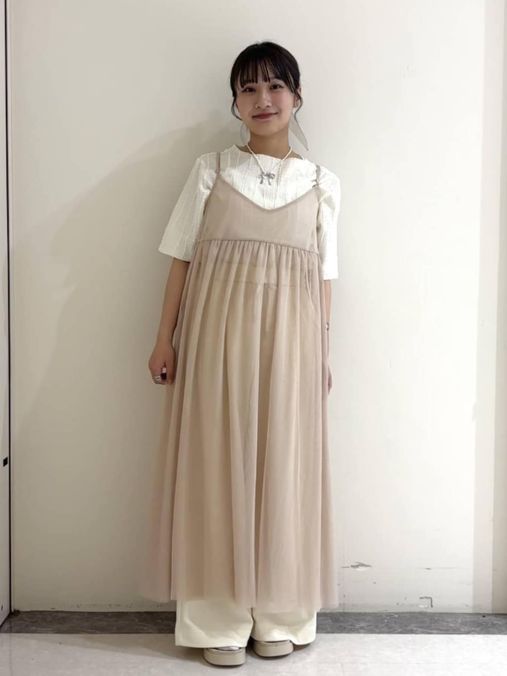 ベージュ系のワンピース、ホワイト系のサンダル、ホワイト系のTシャツ/カットソーを着用したレディースの夏コーディネートの2枚目の写真