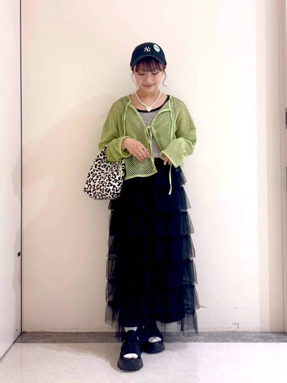 ブラック系のサンダル、グリーン系のニット/セーター、ブラック系のタンクトップを着用したレディースの春コーディネートの4枚目の写真