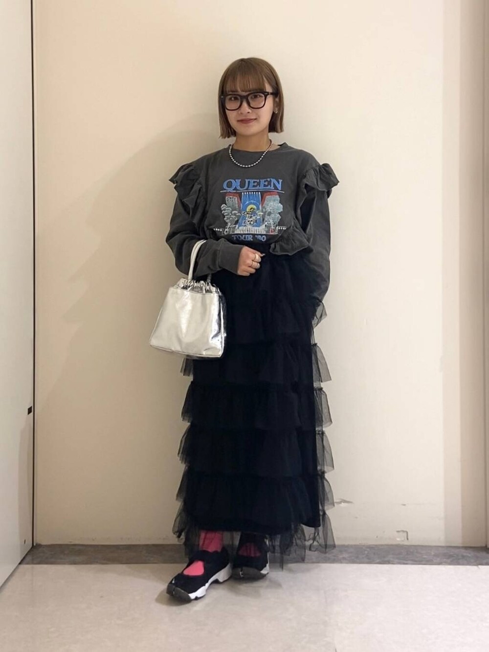 ブラック系のスカート、シルバー系のハンドバッグ、ピンク系のソックス/靴下を着用したレディースの冬コーディネートの2枚目の写真