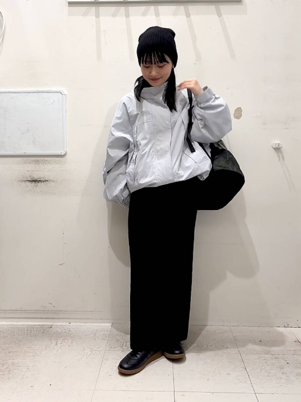 ブルー系のナイロンジャケット、ブラック系のスカート、ブラック系のスニーカーを着用したレディースの春コーディネートの3枚目の写真