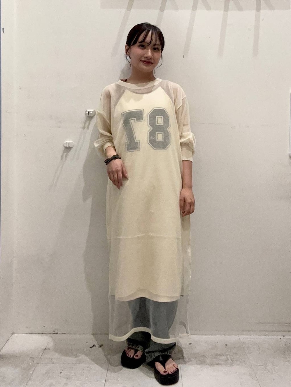 ブルー系のデニムパンツ、ベージュ系のタンクトップ、ブラック系のサンダルを着用したレディースの夏コーディネートの3枚目の写真