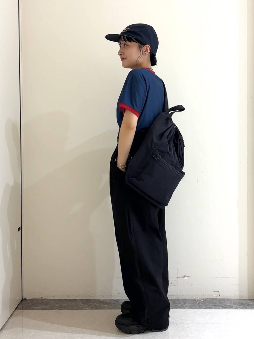 ブラック系のショルダーバッグ、ブルー系のTシャツ/カットソー、ブラック系のスニーカーを着用したレディースの夏コーディネートの3枚目の写真