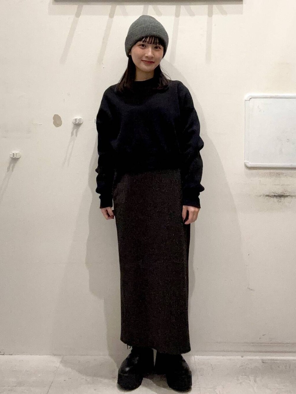ブラック系のニット/セーター、ブラック系のスカート、グレー系のニットキャップ/ビーニーを着用したレディースの冬コーディネートの2枚目の写真