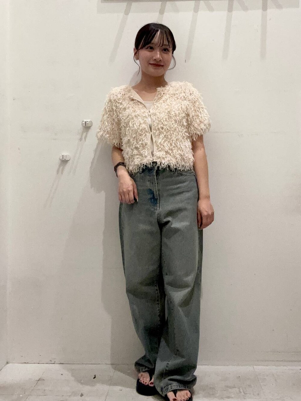 ブルー系のデニムパンツ、ブラック系のサンダル、ホワイト系のキャミソールを着用したレディースの夏コーディネートの2枚目の写真