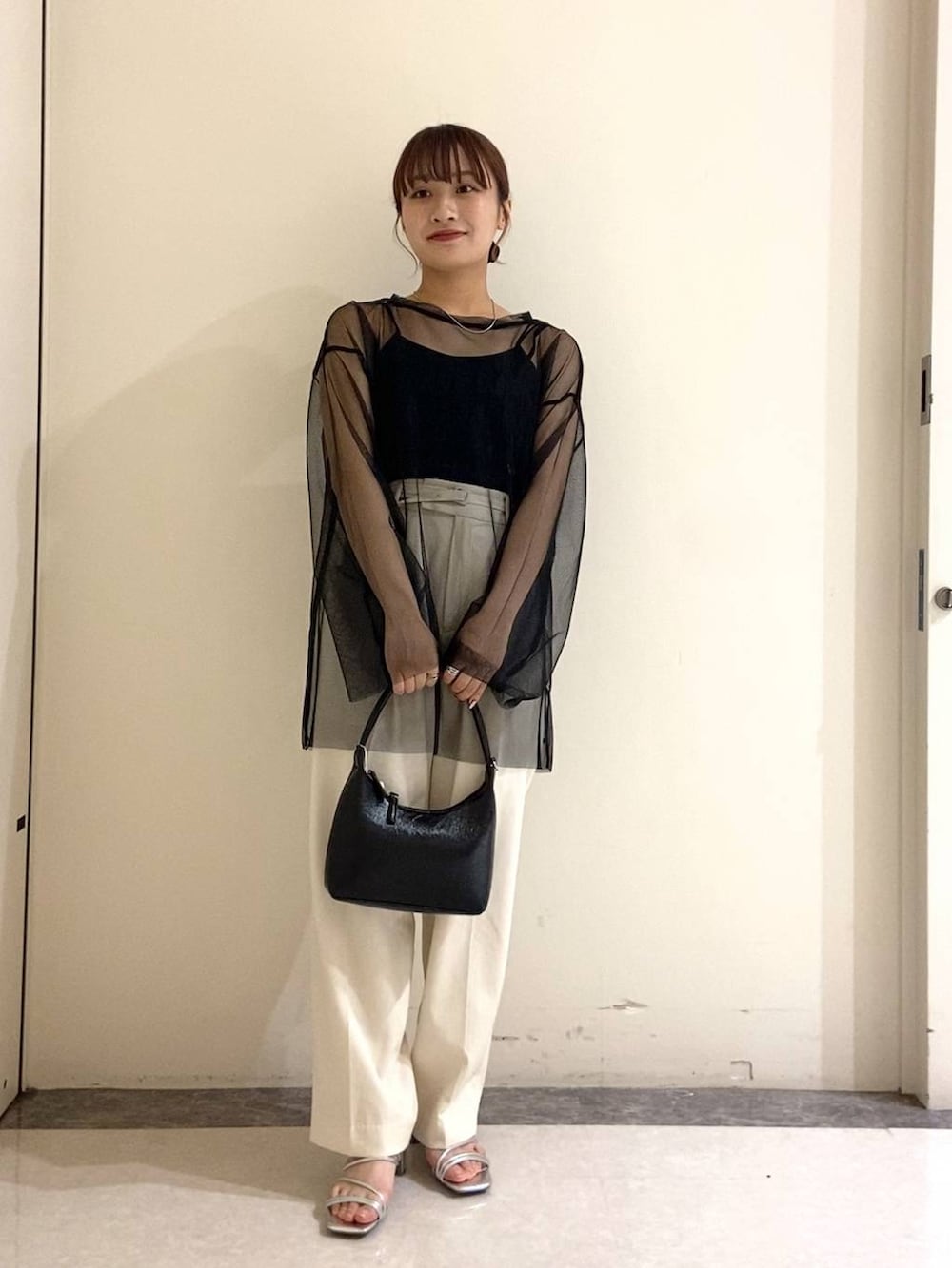 シルバー系のサンダル、ブラック系のTシャツ/カットソー、ブラック系のハンドバッグを着用したレディースの春コーディネートの4枚目の写真