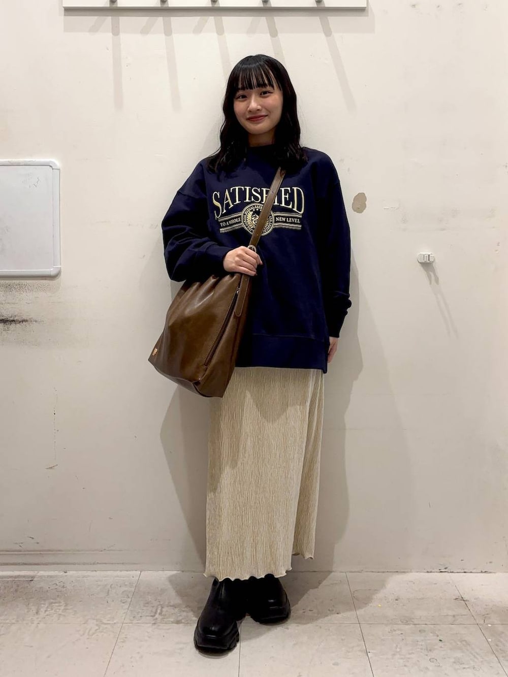 ブラック系のブーツ、ホワイト系のスカート、ブラウン系のショルダーバッグを着用したレディースの冬コーディネートの2枚目の写真