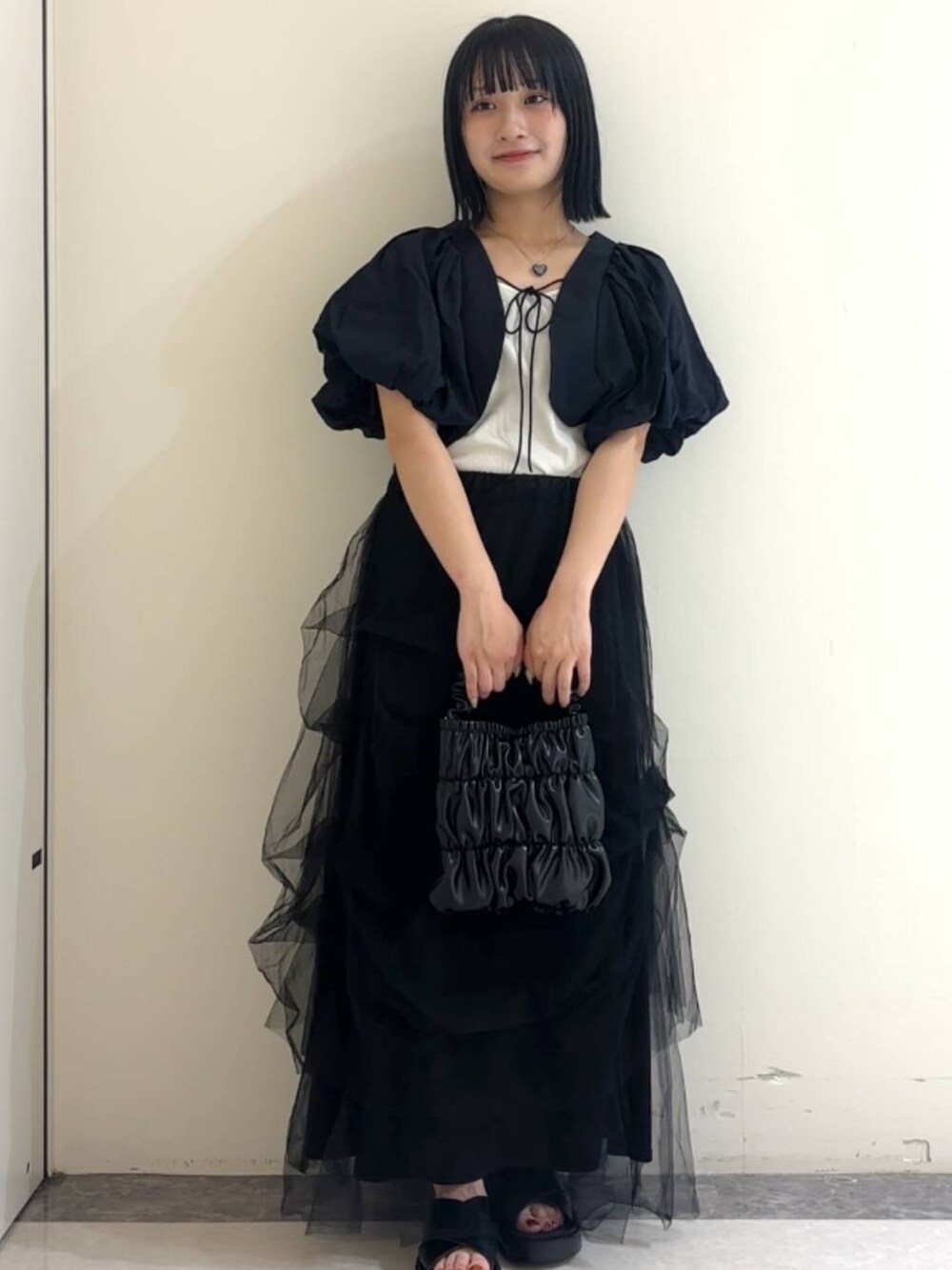 ブラック系のカーディガン/ボレロ、ブラック系のサンダル、ホワイト系のキャミソールを着用したレディースの夏コーディネートの2枚目の写真