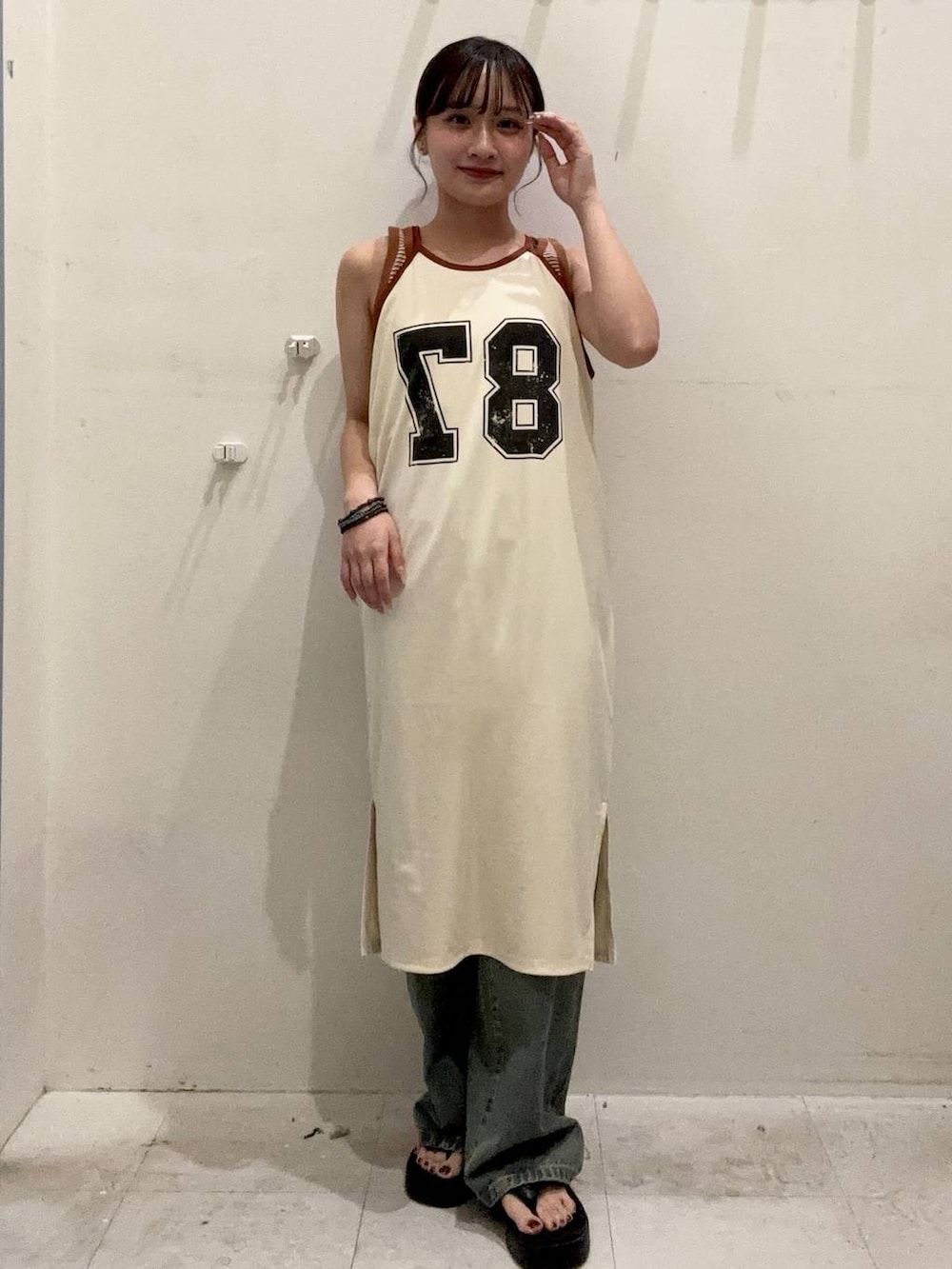 ブルー系のデニムパンツ、ベージュ系のタンクトップ、ブラック系のサンダルを着用したレディースの夏コーディネートの2枚目の写真