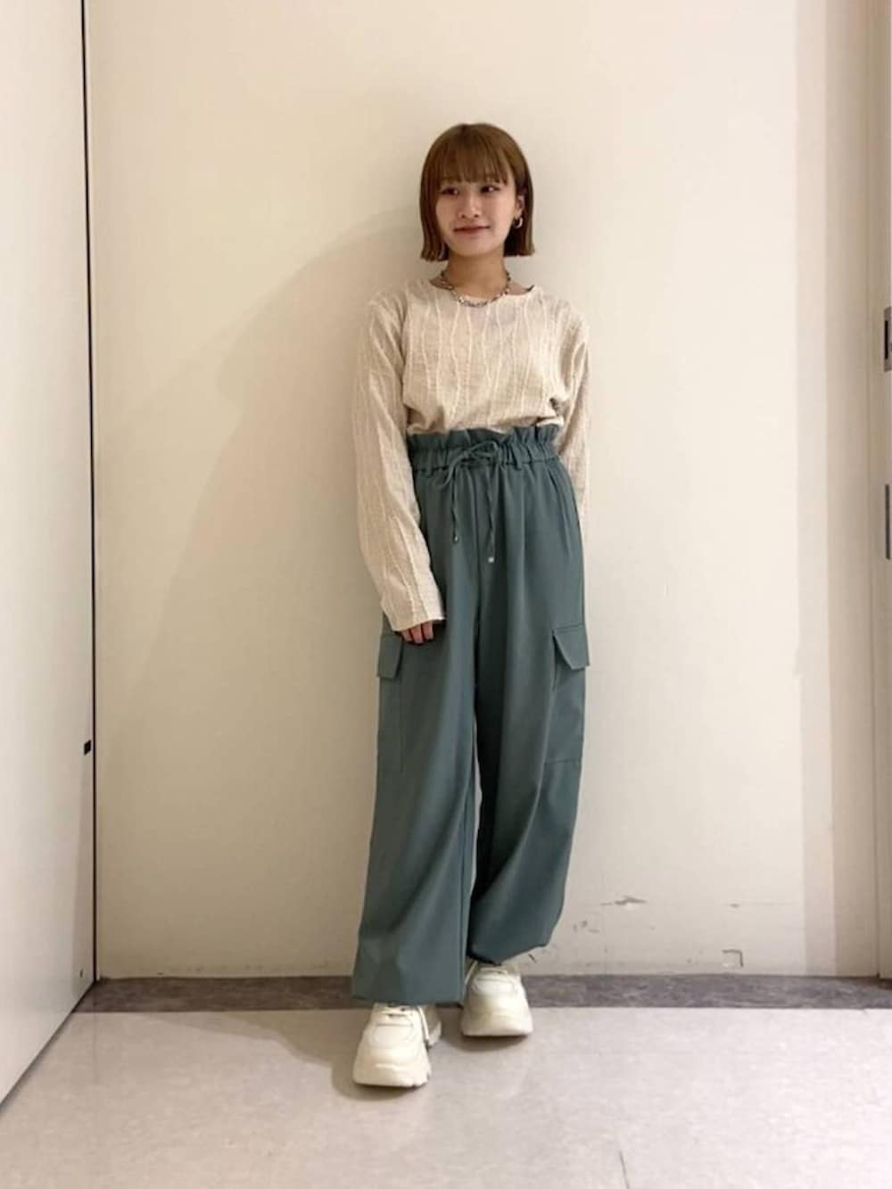 ベージュ系のTシャツ/カットソー、グリーン系のその他パンツ、ホワイト系のスニーカーを着用したレディースの冬コーディネートの2枚目の写真