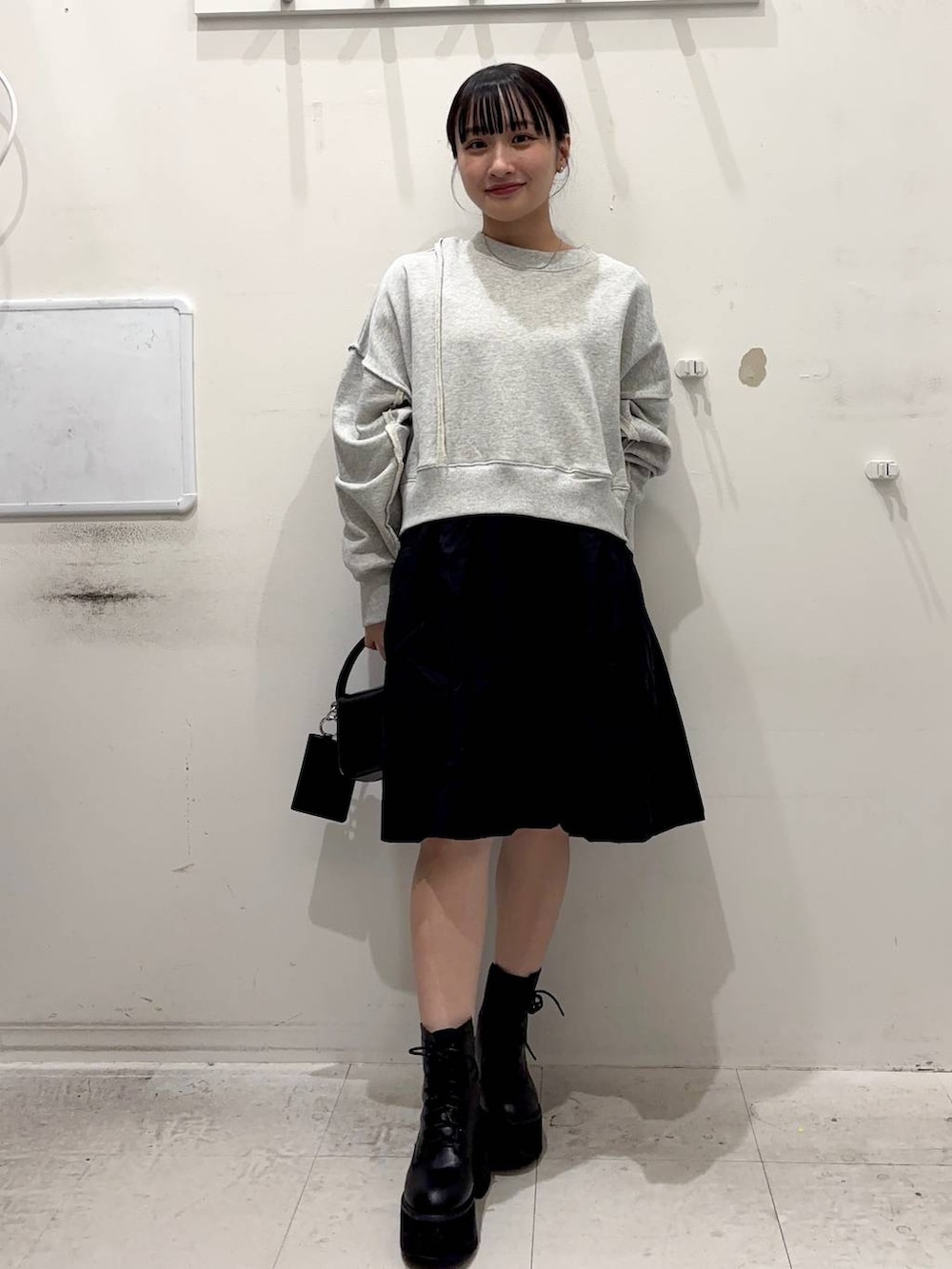 ブラック系のショルダーバッグ、グレー系のワンピース、ホワイト系のネックレスを着用したレディースの春コーディネートの3枚目の写真