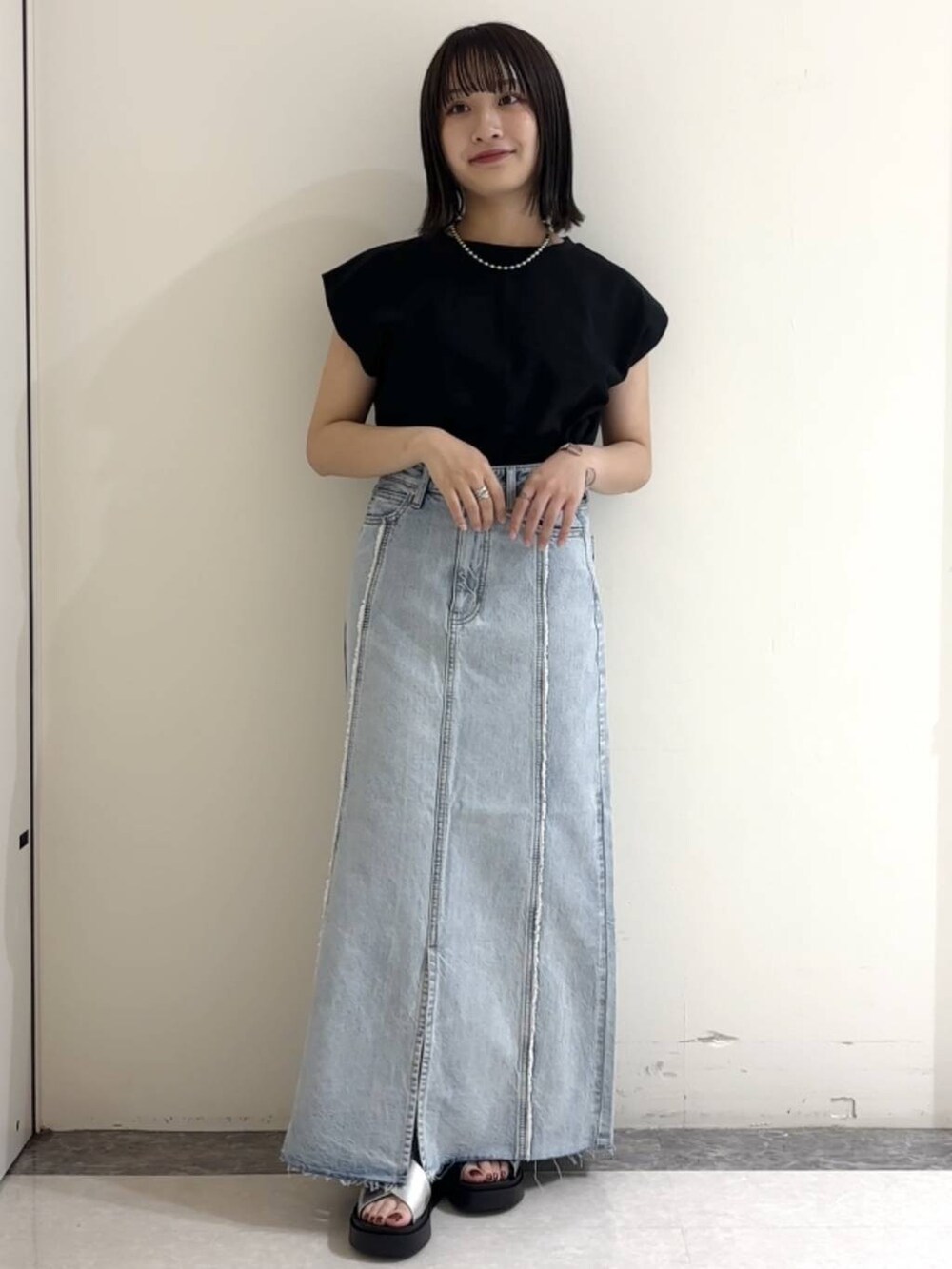 シルバー系のサンダル、ブルー系のスカート、ブラック系のTシャツ/カットソーを着用したレディースの夏コーディネートの2枚目の写真