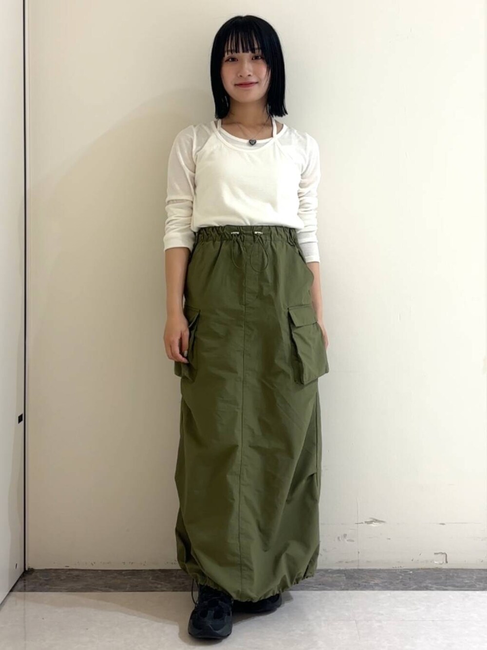 ホワイト系のTシャツ/カットソー、グリーン系のスカート、ブラック系のネックレスを着用したレディースの春コーディネートの2枚目の写真