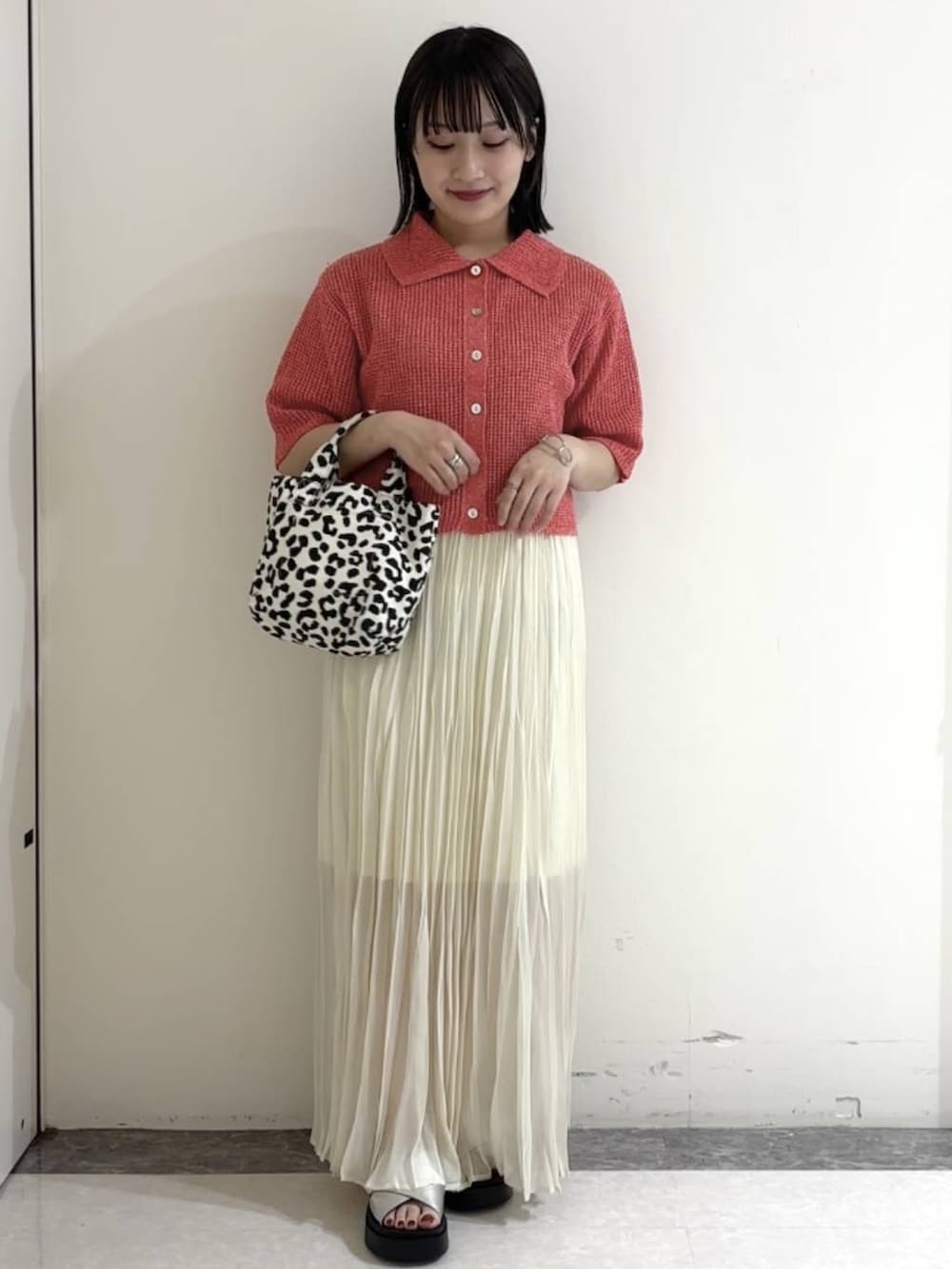 オレンジ系のニット/セーター、シルバー系のサンダル、ホワイト系のスカートを着用したレディースの夏コーディネートの3枚目の写真