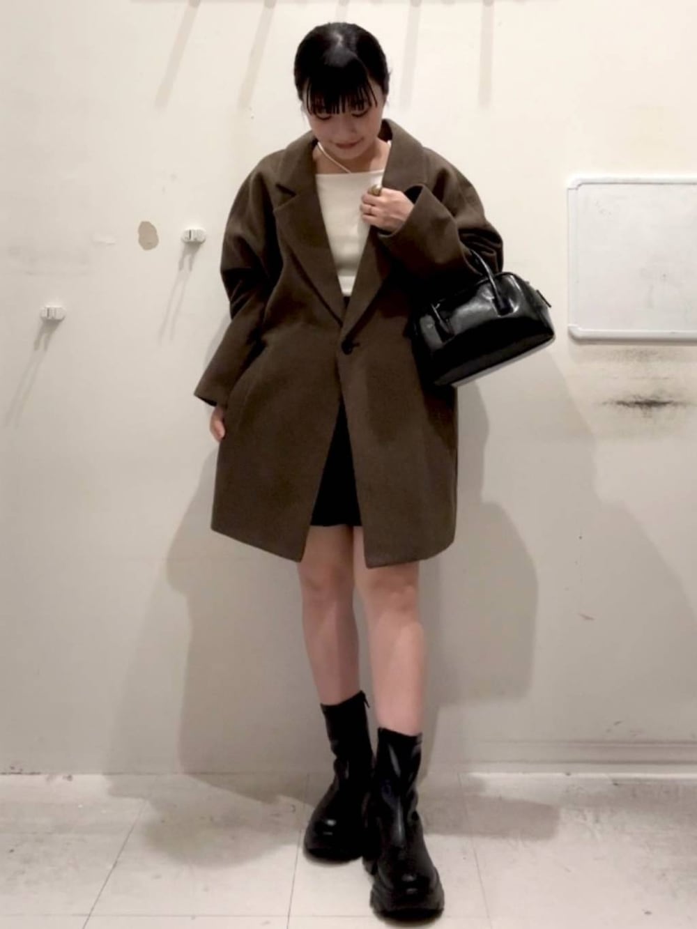 ブラウン系のチェスターコート、ブラック系のその他パンツ、ブラック系のブーツを着用したレディースの秋コーディネートの2枚目の写真