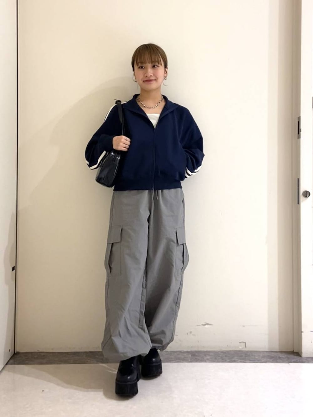 ブラック系のハンドバッグ、ブルー系のTシャツ/カットソー、グレー系のカーゴパンツを着用したレディースの春コーディネートの2枚目の写真