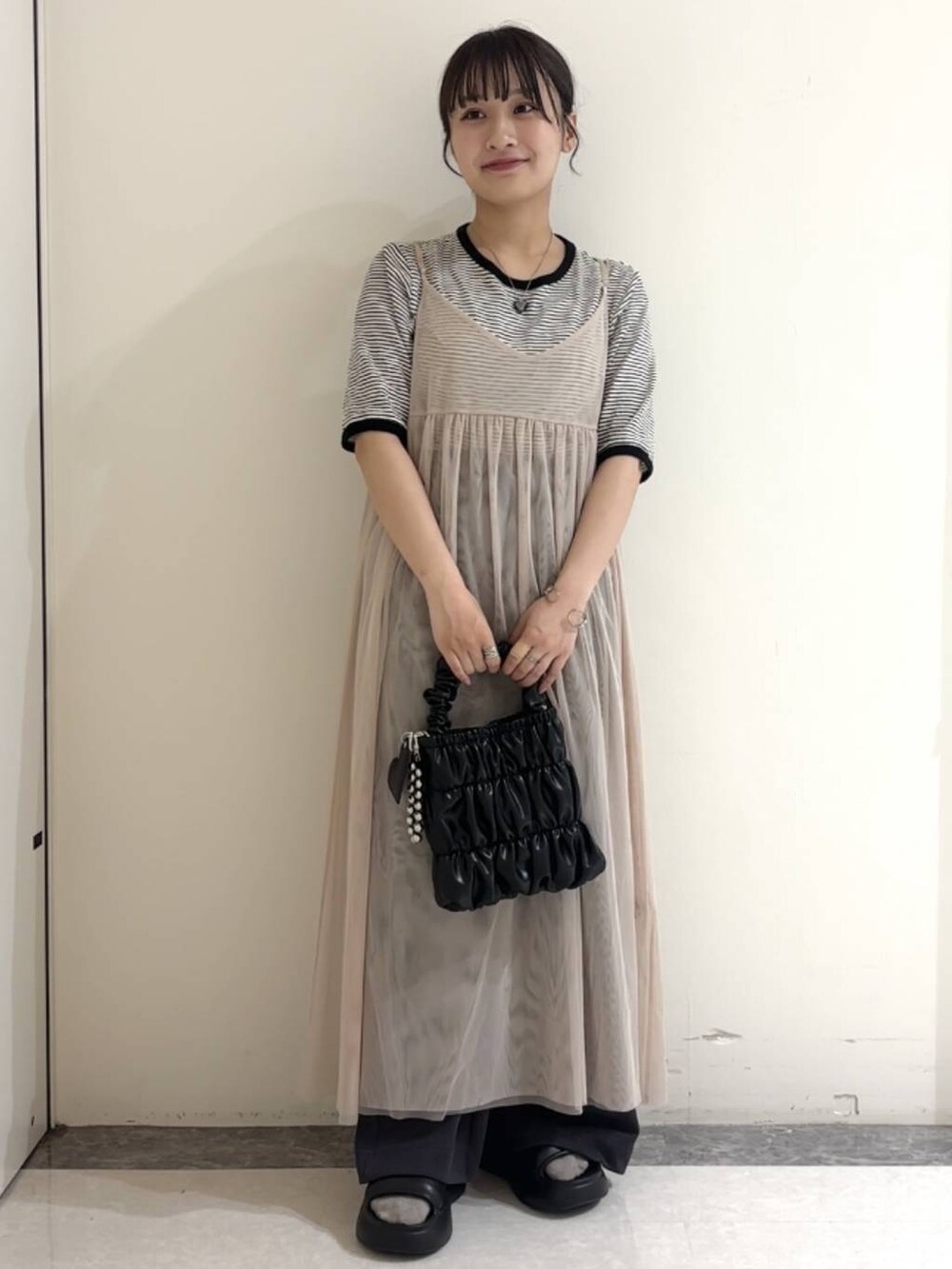 ブラック系のサンダル、ベージュ系のワンピース、その他のTシャツ/カットソーを着用したレディースの夏コーディネートの2枚目の写真