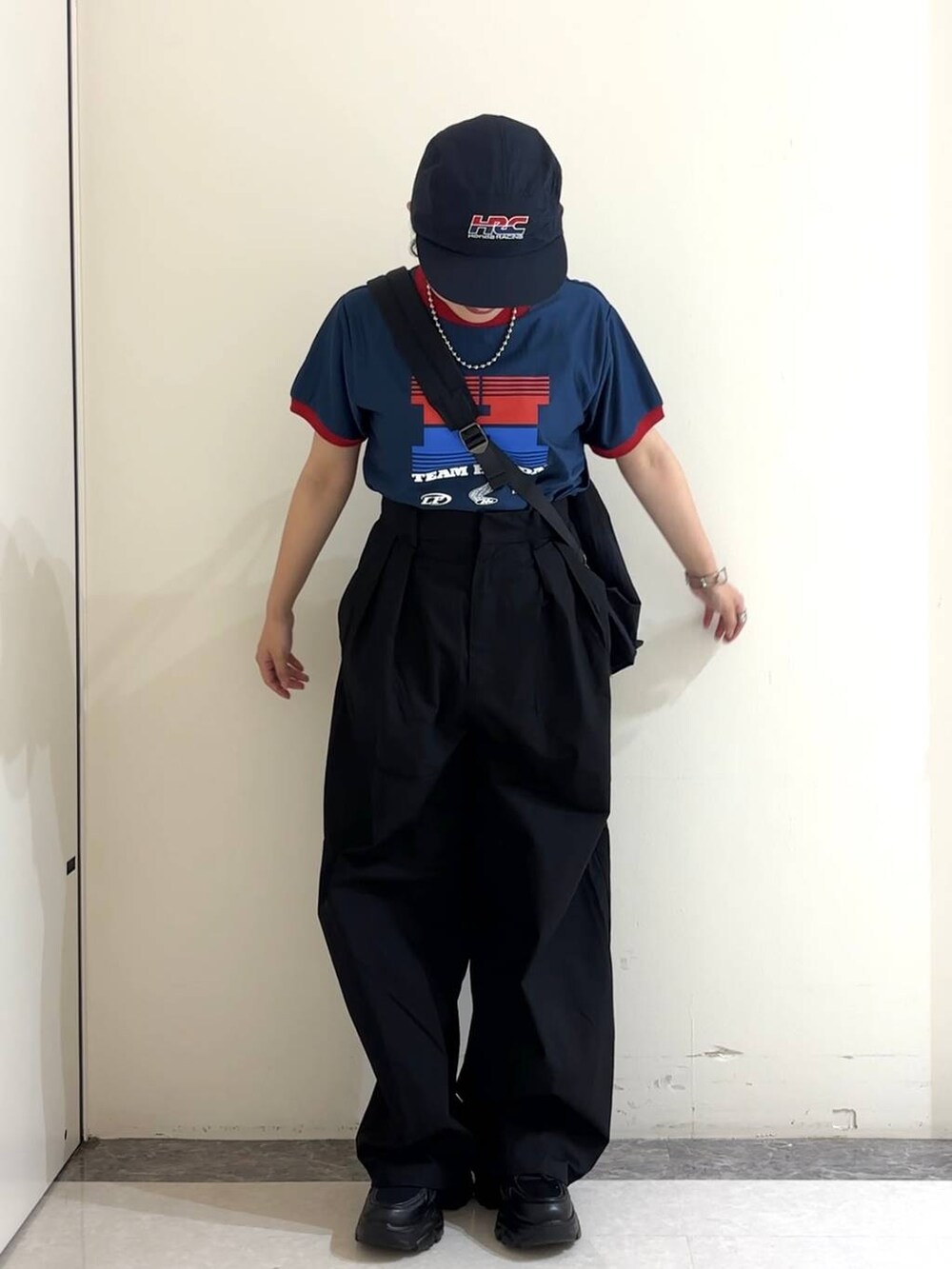 ブラック系のショルダーバッグ、ブルー系のTシャツ/カットソー、ブラック系のスニーカーを着用したレディースの夏コーディネートの2枚目の写真