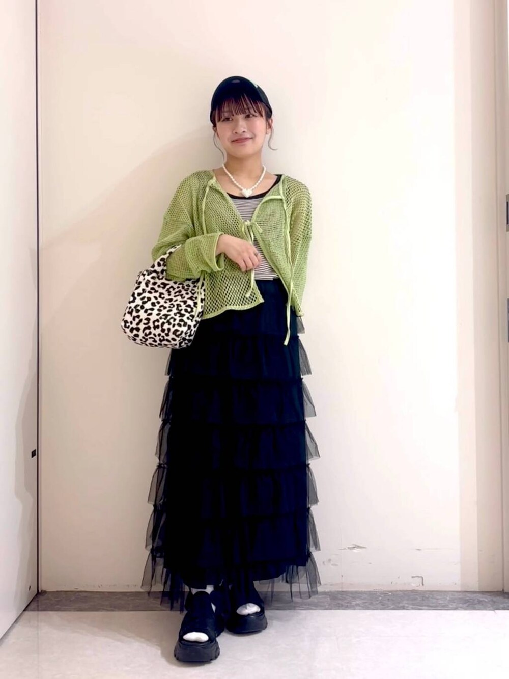 ブラック系のサンダル、グリーン系のニット/セーター、ブラック系のタンクトップを着用したレディースの春コーディネートの2枚目の写真