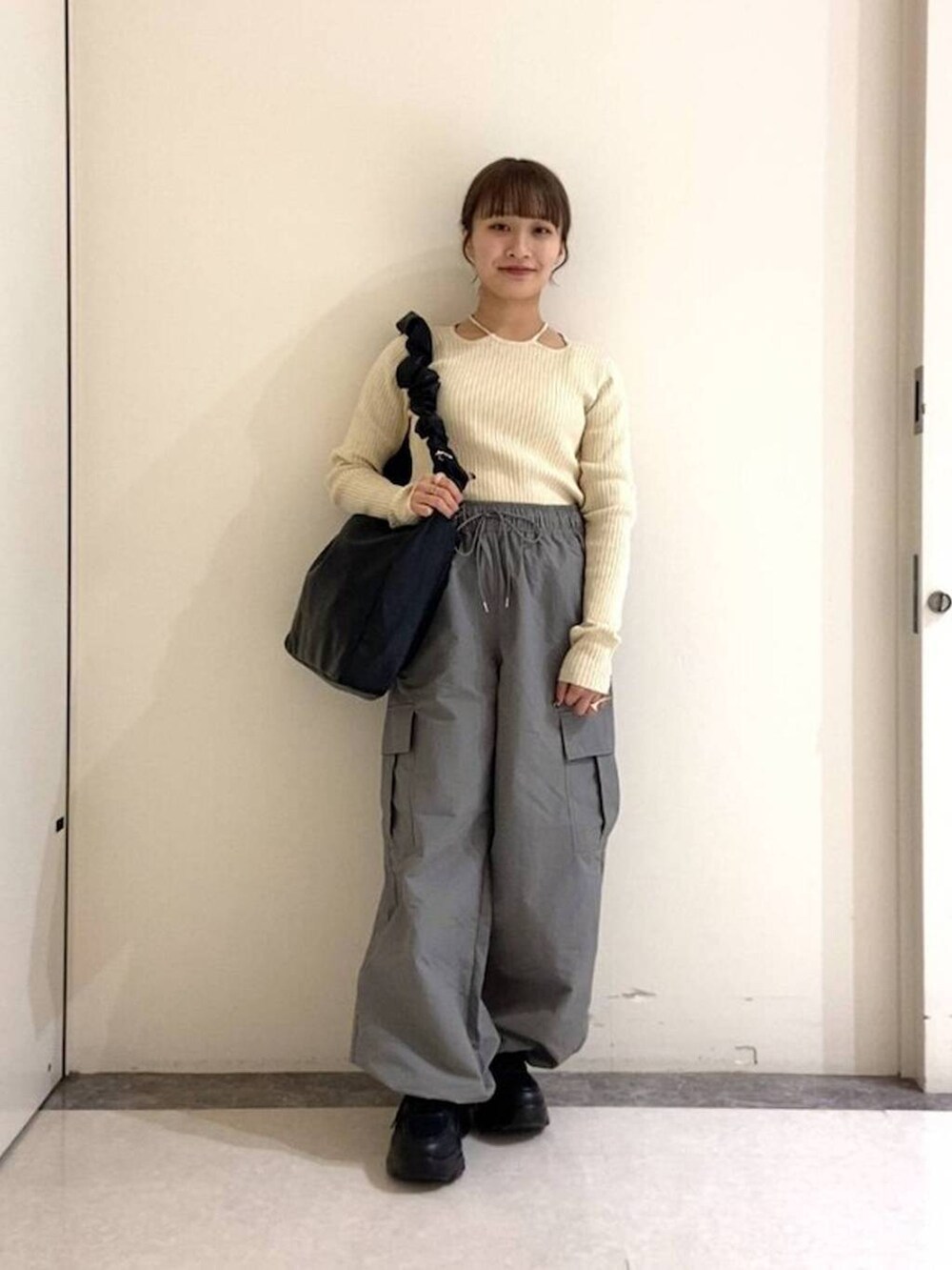 ベージュ系のニット/セーター、グレー系のカーゴパンツ、ブラック系のショルダーバッグを着用したレディースの春コーディネートの2枚目の写真