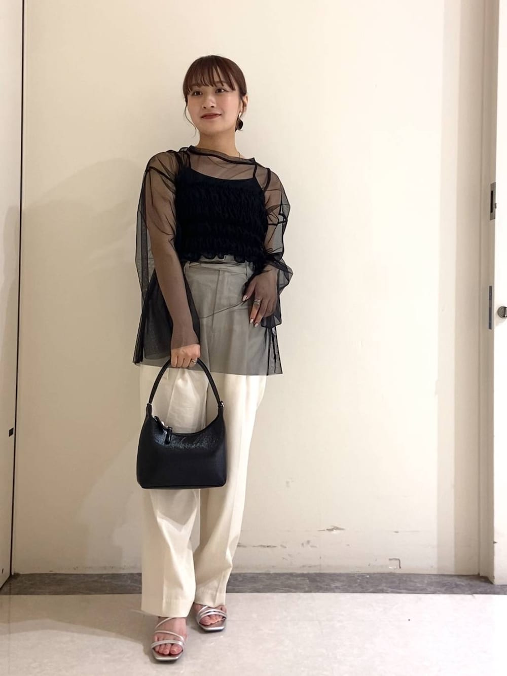 シルバー系のサンダル、ブラック系のTシャツ/カットソー、ブラック系のハンドバッグを着用したレディースの春コーディネートの2枚目の写真