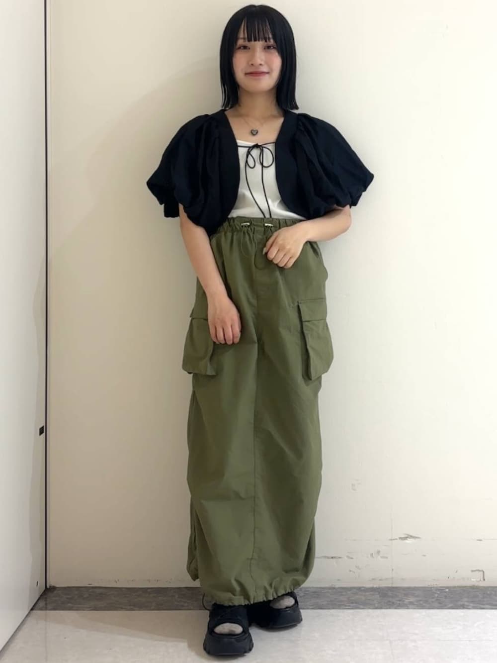 ブラック系のサンダル、ブラック系のカーディガン/ボレロ、ホワイト系のキャミソールを着用したレディースの春コーディネートの2枚目の写真