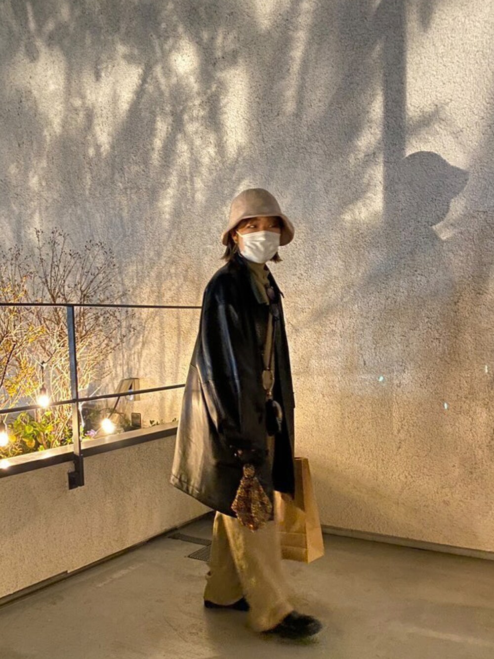 ブラック系のステンカラーコート、その他のバッグ、ベージュ系のつなぎ/オールインワンを着用したレディースの春コーディネートの2枚目の写真