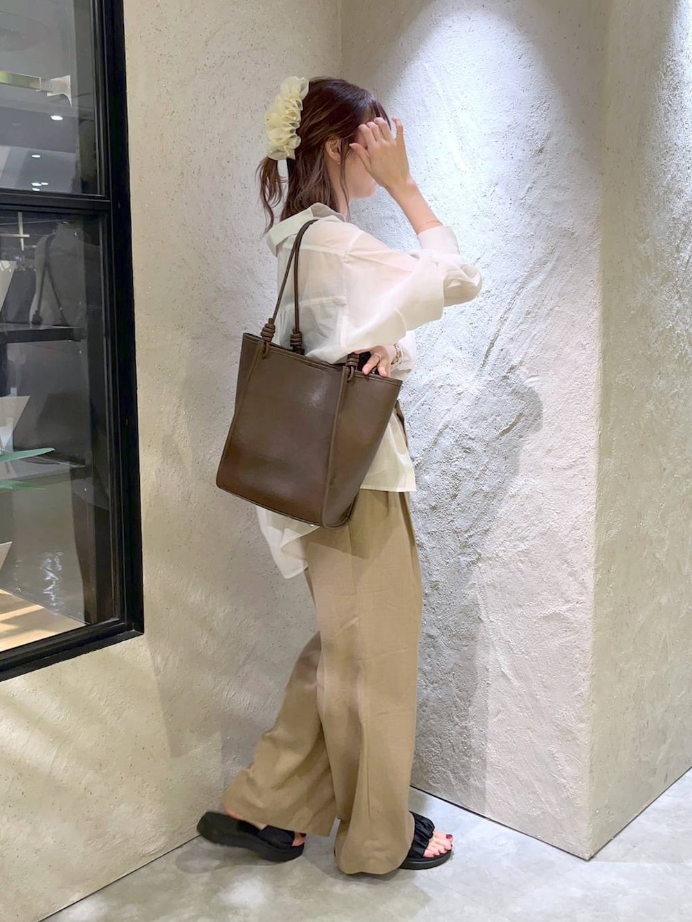 ホワイト系のシャツ/ブラウス、ベージュ系のスラックス、ブラック系のサンダルを着用したレディースの夏コーディネートの2枚目の写真