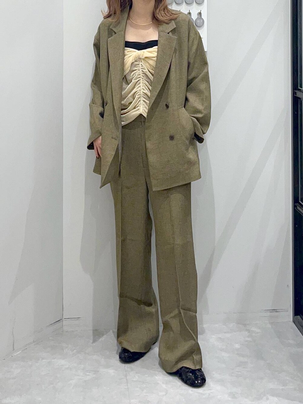 ブラウン系のテーラードジャケット、ブラック系のバレエシューズ、ベージュ系のベストを着用したレディースの秋コーディネートの2枚目の写真