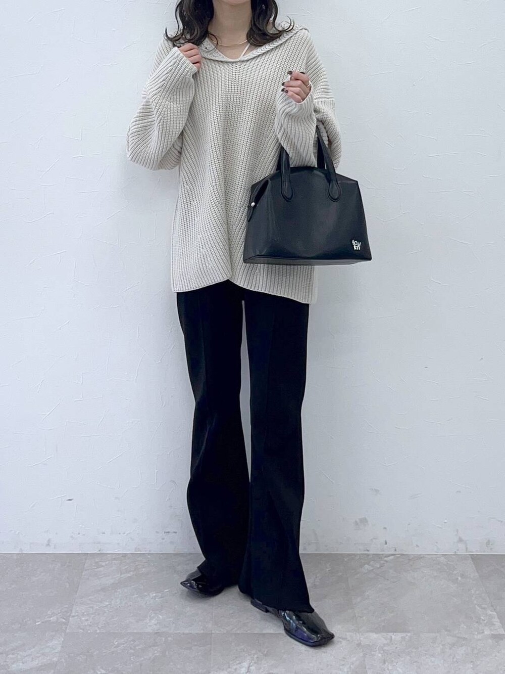 ホワイト系のニット/セーター、ブラック系のショルダーバッグを着用したレディースの秋コーディネートの2枚目の写真