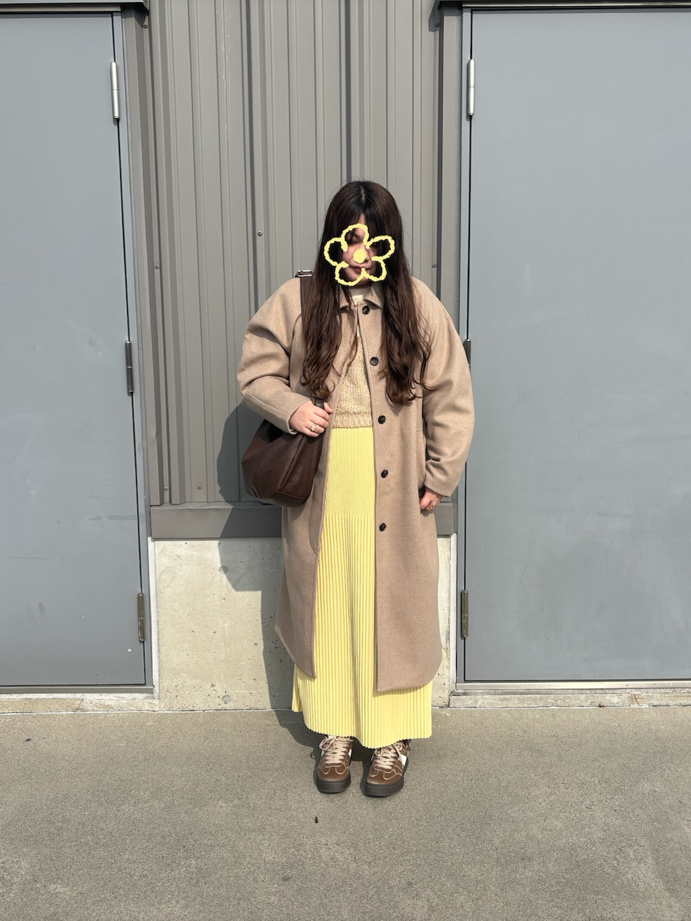 ベージュ系のベスト、イエロー系のスカート、ベージュ系のスニーカーを着用したレディースの冬コーディネートの2枚目の写真