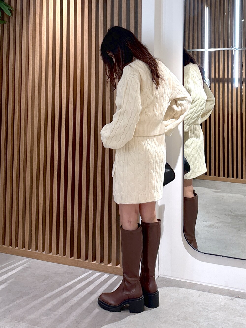 ホワイト系のワンピース、ブラウン系のブーツ、ブラック系のトートバッグを着用したレディースの冬コーディネートの2枚目の写真