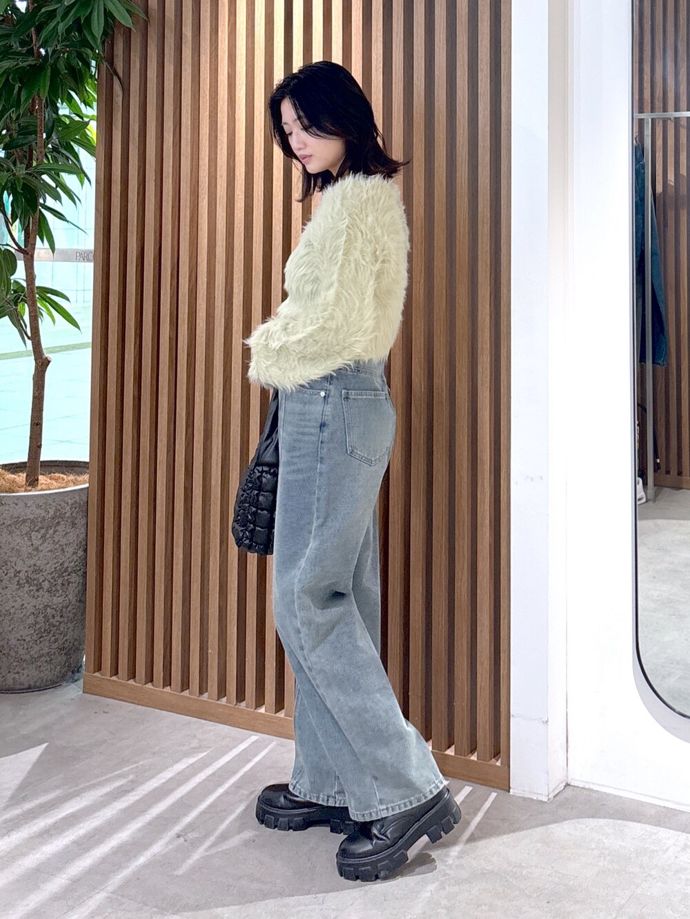 ベージュ系のニット/セーター、ブルー系のデニムパンツ、ブラック系のハンドバッグを着用したレディースの冬コーディネートの2枚目の写真