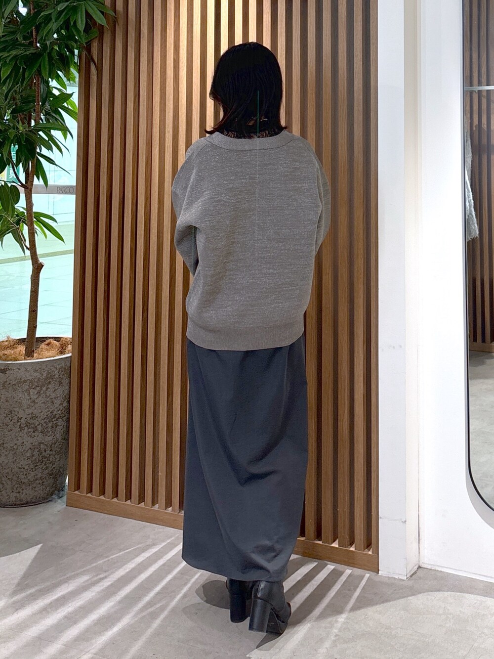 グレー系のカーディガン/ボレロ、グレー系のスカート、ブラック系のショルダーバッグを着用したレディースの冬コーディネートの2枚目の写真