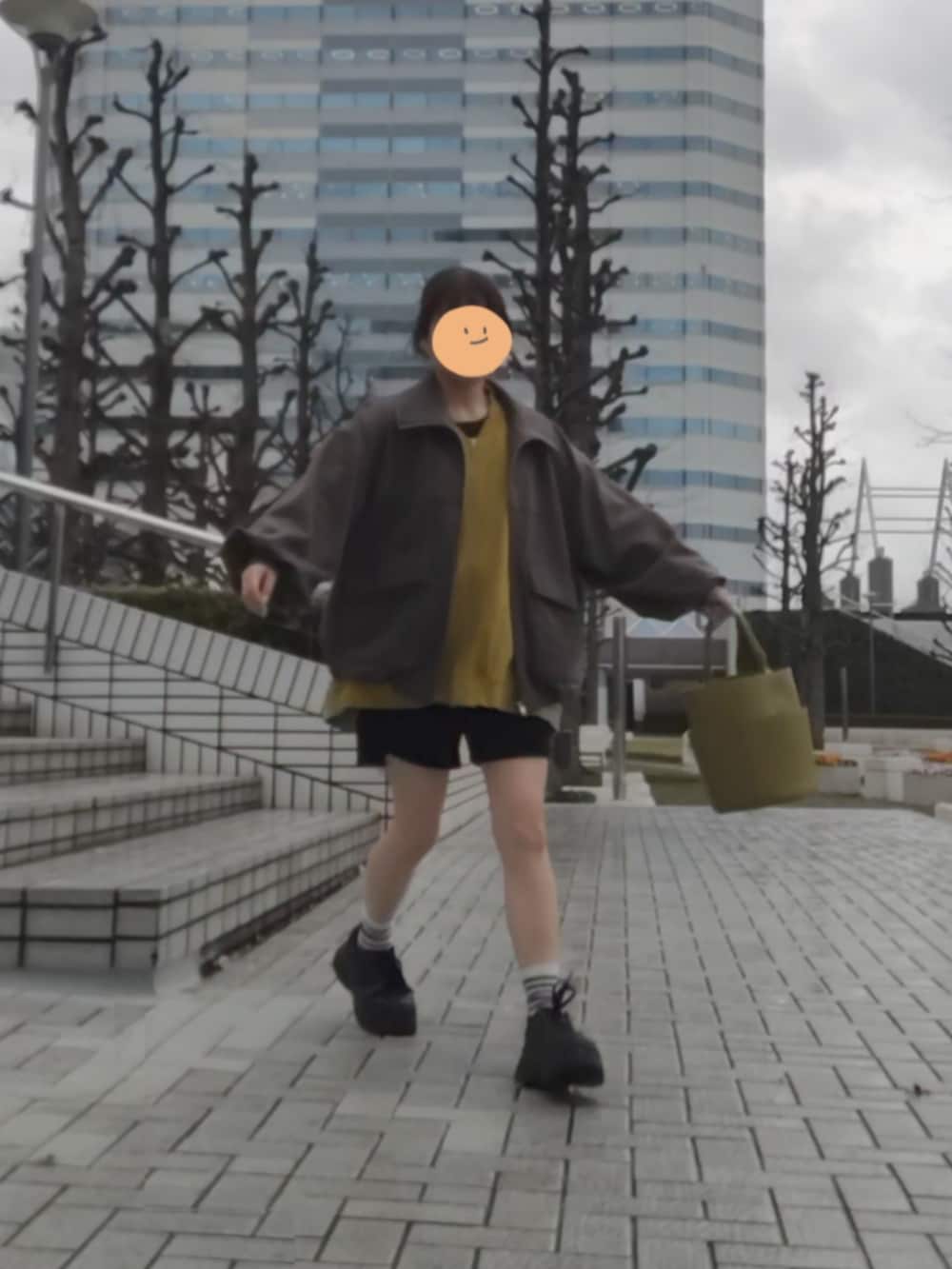 グレー系のブルゾン、イエロー系のトップス、ブラック系のスニーカーを着用したレディースの春コーディネートの2枚目の写真