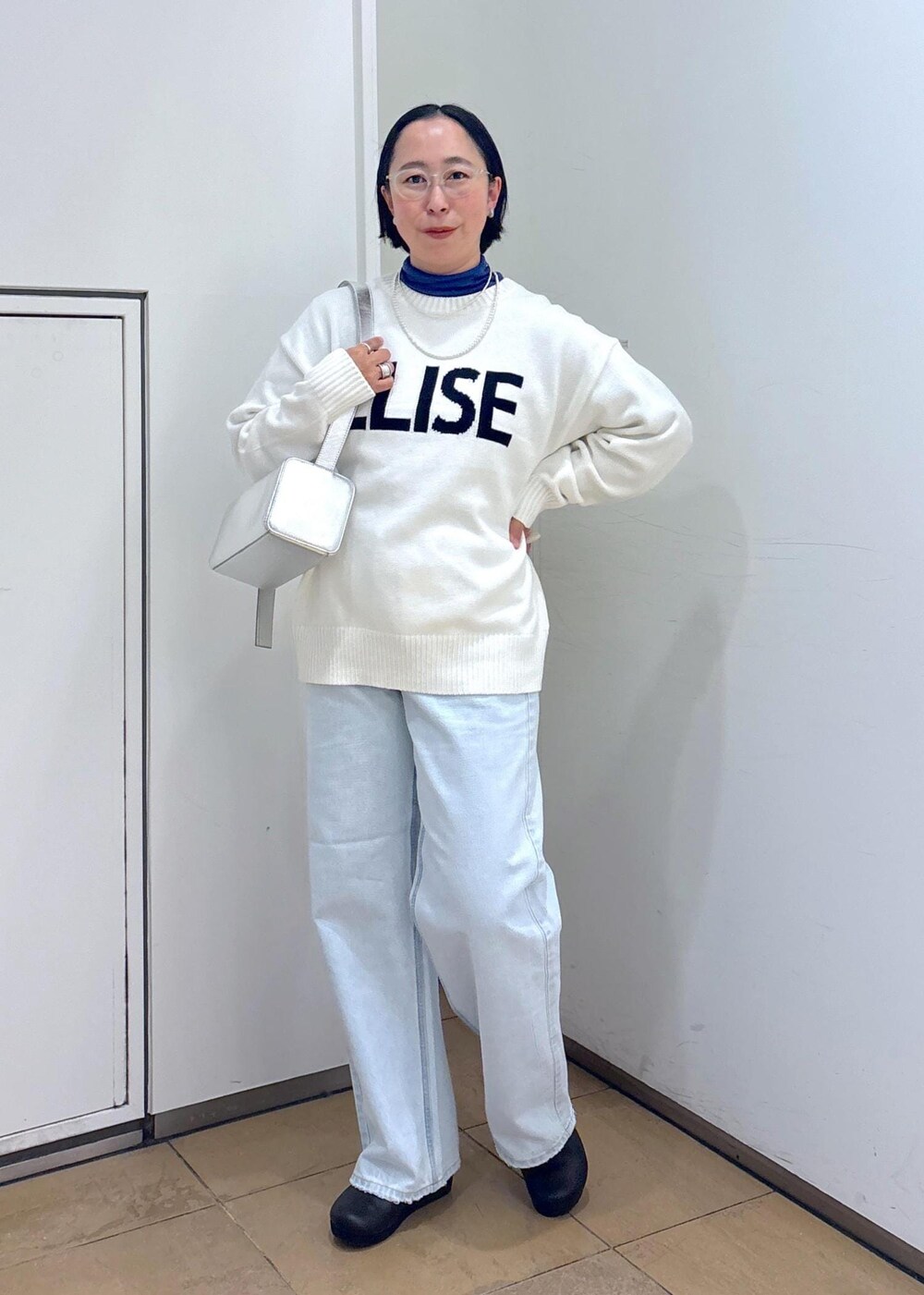 ホワイト系のニット/セーター、シルバー系のショルダーバッグ、ブルー系のデニムパンツを着用したレディースの冬コーディネートの3枚目の写真