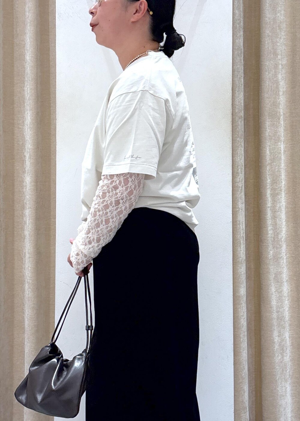 ブラック系のスカート、ホワイト系のその他トップス、ブラウン系のハンドバッグを着用したレディースの夏コーディネートの7枚目の写真