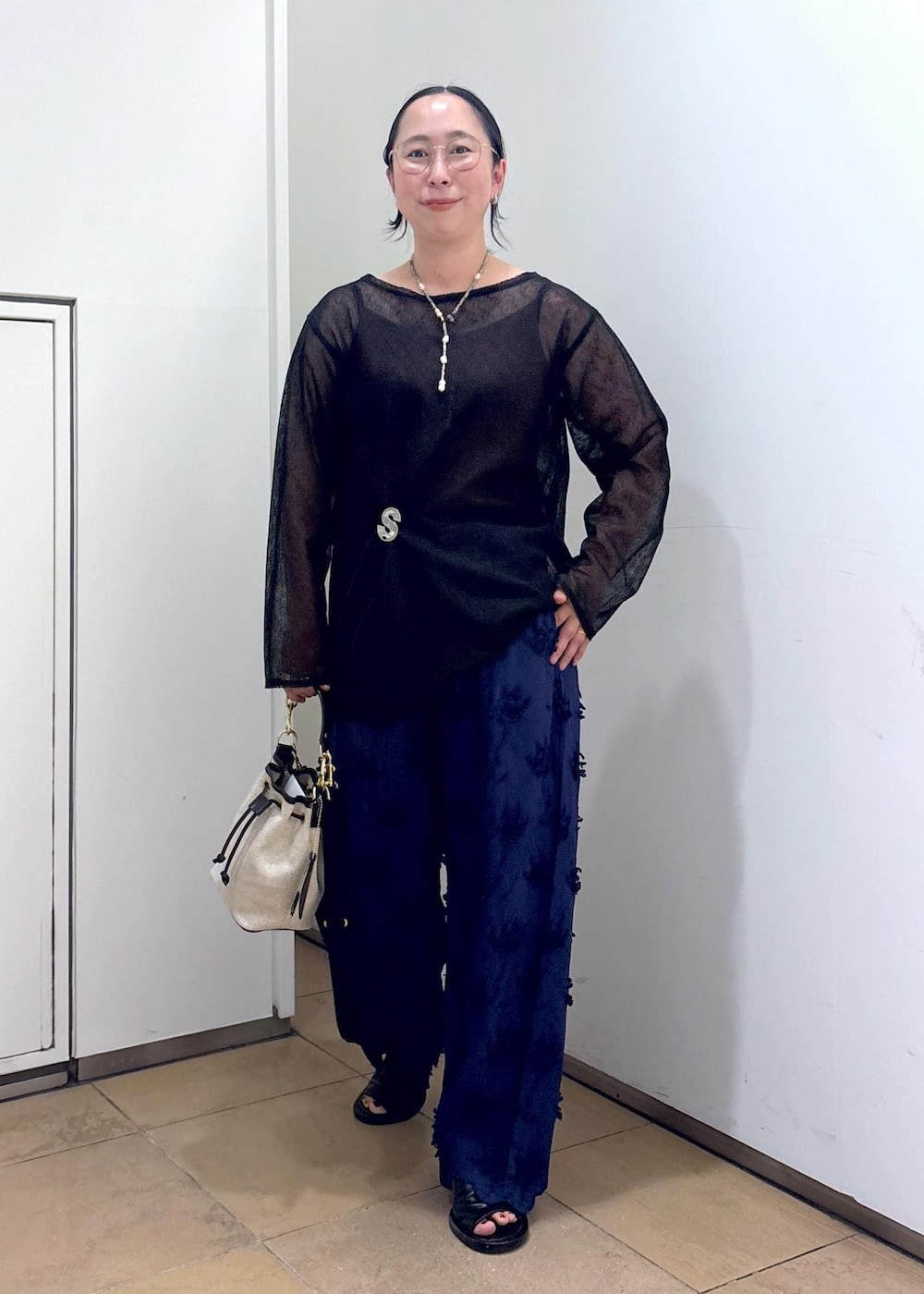 ブラック系のニット/セーター、ブルー系のその他パンツ、ホワイト系のショルダーバッグを着用したレディースの夏コーディネートの3枚目の写真