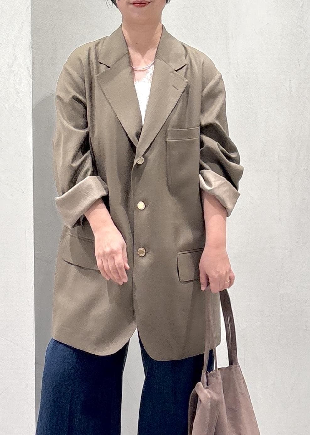 ブラウン系のパンプス、ホワイト系のキャミソール、ブルー系のデニムパンツを着用したレディースの冬コーディネートの7枚目の写真