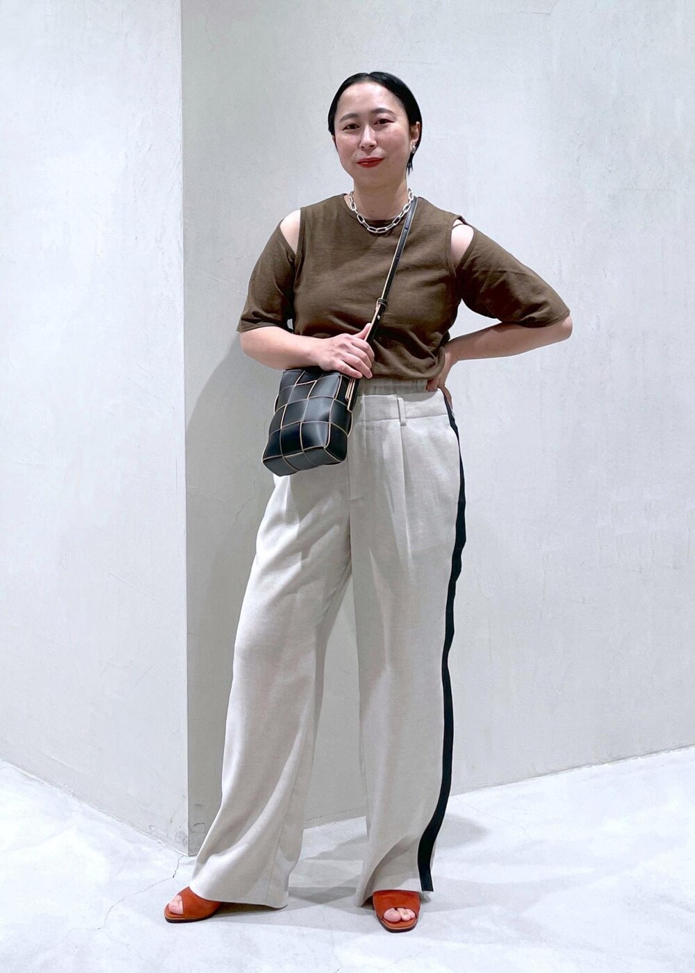 ブラック系のショルダーバッグ、ホワイト系のその他パンツ、ブラウン系のTシャツ/カットソーを着用したレディースの春コーディネートの2枚目の写真